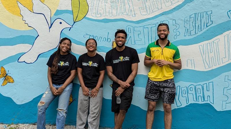 Four students stand in front of painted wall